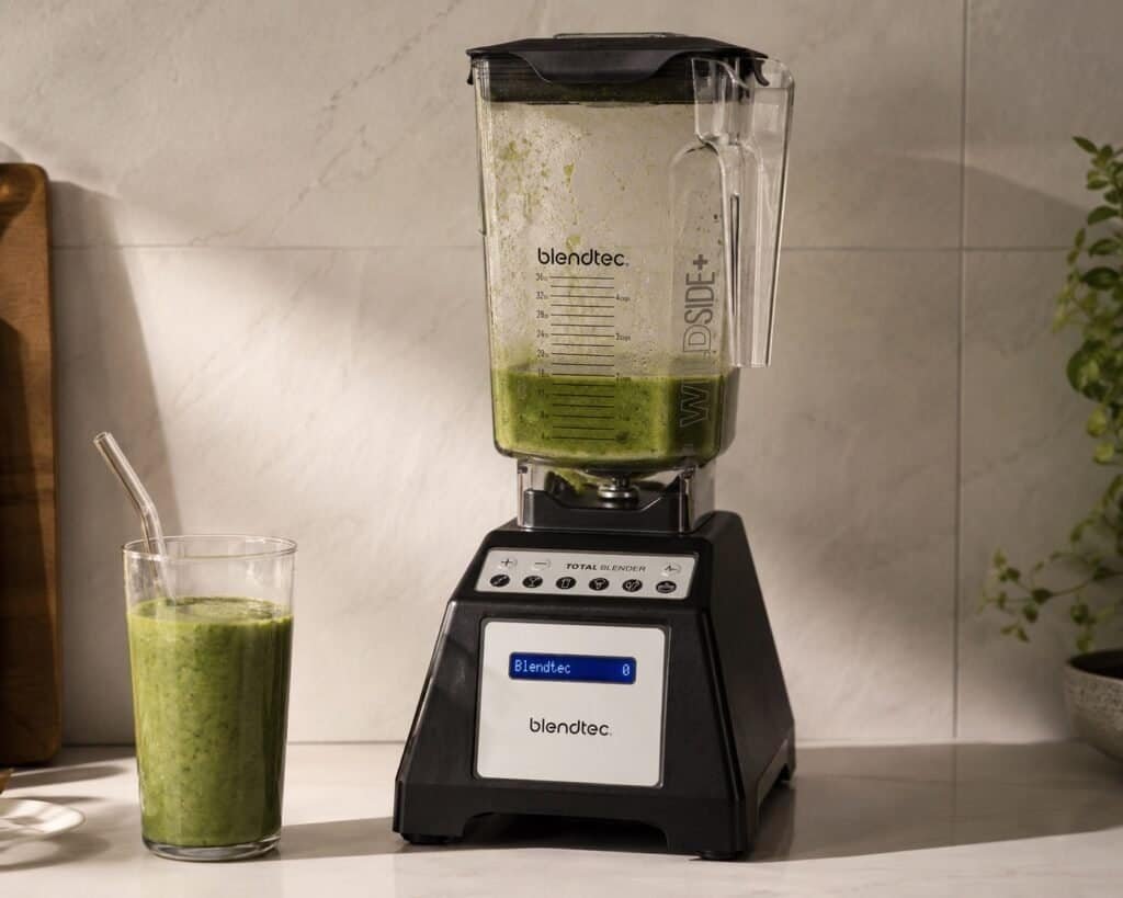 Blendtec Total Classic blender with WildSide+ jar on a kitchen counter next to fresh fruit and vegetables
