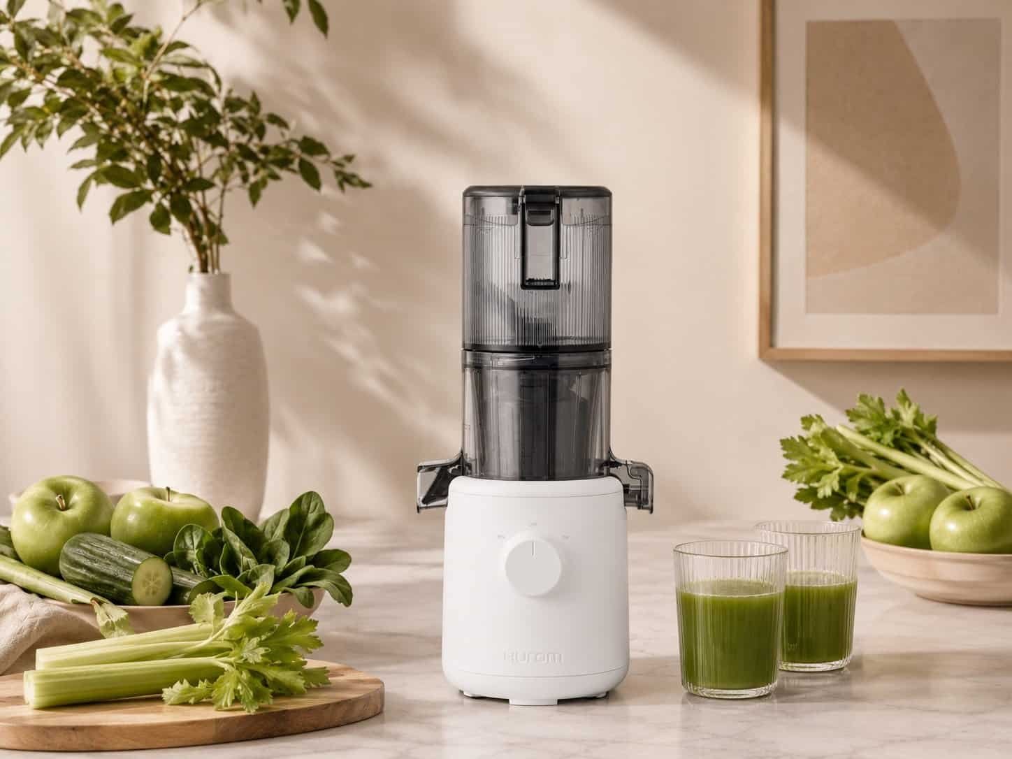 Hurom juicer review – H310 compact slow juicer in white with celery and green juice on marble counter