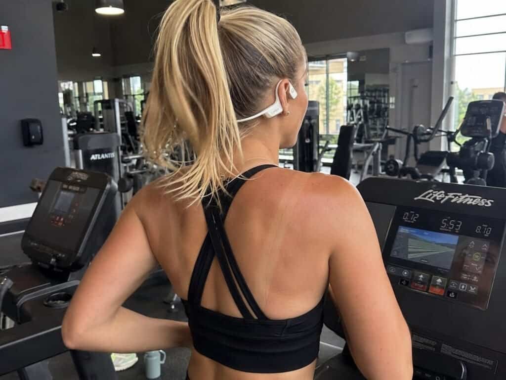 Woman wearing Shokz OpenRun Pro 2 open-ear headphones while training on a treadmill